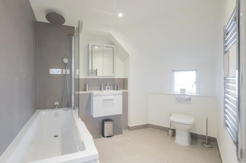 uma casa de banho com uma banheira, um WC e um lavatório. em Luxury City Centre Flat with Stunning Water View em Cambridge