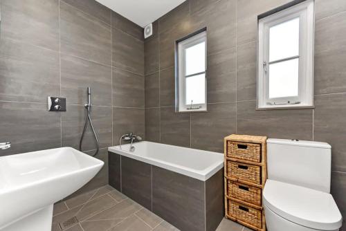 uma casa de banho com uma banheira, um WC e 2 janelas. em Beautiful Family Victorian Home em Crystal Palace