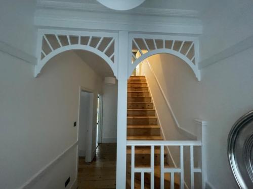 a staircase in a house with white walls and wooden floors at Beautiful Family Victorian Home in Crystal Palace