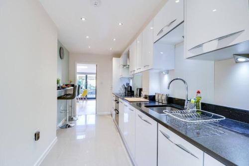 a kitchen with white cabinets and black counter tops at Charming and Modern 2 Bedroom House with Parking in Cambridge