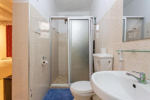 a bathroom with a shower and a toilet and a sink at Bonsai Villa in Nairobi