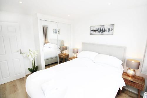 a white bedroom with a bed and a mirror at Modern and Cosy Flat For 4 in Cherry Hinton
