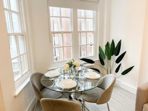 a dining room with a glass table and chairs at Vibrant 2-Bedroom Flat with Elevator in Marylebone, Close to Hyde Park & Edgware Road in London