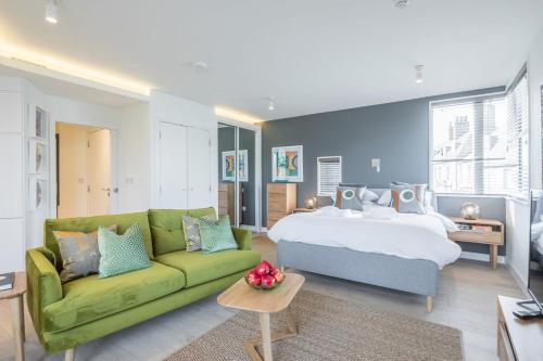 een slaapkamer met een bed en een groene bank bij Luxurious Central Apartment with Balcony in Cambridge