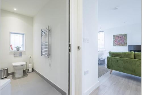 a bathroom with a toilet and a green couch at Luxurious Central Apartment with Balcony in Cambridge