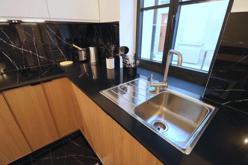 - une cuisine avec un plan de travail noir dans l'établissement Neuf & Cosy - 2 chambres - 11e, à Paris