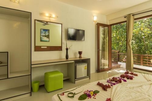 a bedroom with a bed and a mirror and a television at Liberty Guesthouse Maldives in Mahibadhoo