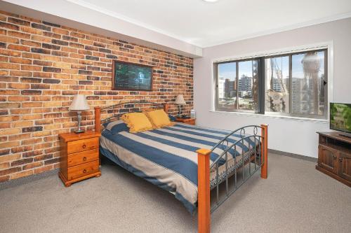 - une chambre avec un lit et un mur en briques dans l'établissement Mainsail 3, à Port Macquarie