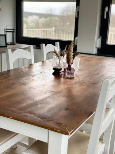 a wooden dining table with white chairs around it at BG Apartments in Somogyhatvan