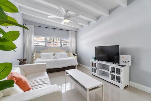 a white living room with a bed and a tv at Coconut Walk To The BeachComfy Beds Firepit Pool in Fort Lauderdale