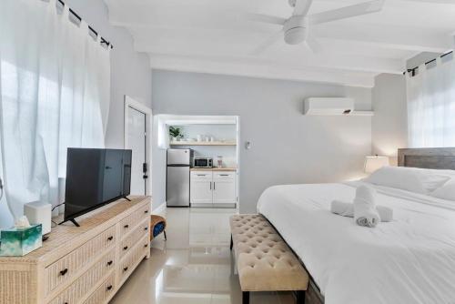 a white bedroom with a large bed and a flat screen tv at The Sandbar Walk To Beach Comfy Beds Firepit Pool in Fort Lauderdale