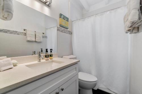 a white bathroom with a sink and a toilet at The Sandbar Walk To Beach Comfy Beds Firepit Pool in Fort Lauderdale