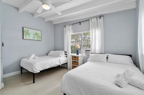 um quarto branco com 2 camas e uma janela em Seashell Walk To The Beach Comfy Beds Firepit Pool em Fort Lauderdale
