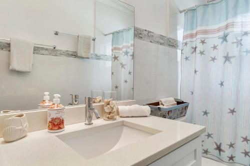 Baño blanco con lavabo y espejo en Seashell Walk To The Beach Comfy Beds Firepit Pool, en Fort Lauderdale