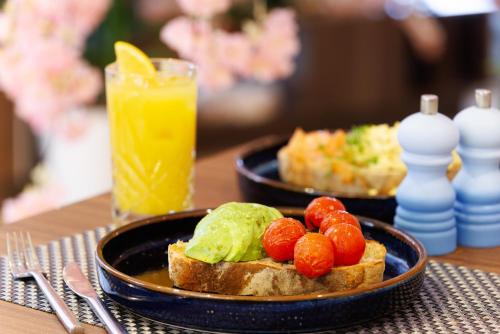 a plate of food with toast and tomatoes and a glass of orange juice at DoubleTree by Hilton London Angel Kings Cross in London