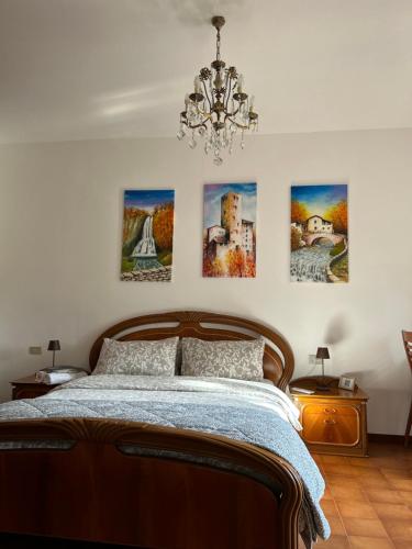 ein Schlafzimmer mit einem Bett mit vier Gemälden an der Wand in der Unterkunft Villa Dei Cedri in Asso