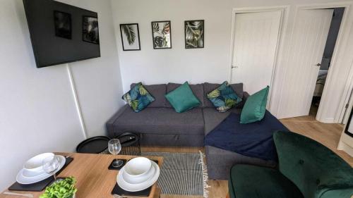 uma sala de estar com um sofá e uma mesa em OPP Sidmouth - Cosy Coastal Chalet great views! BIG SAVINGS booking 7 days or more! - Dogs by Request Only em Sidmouth