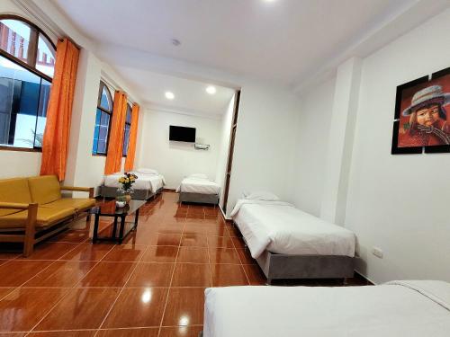 una camera con 3 letti, un divano e una TV di Munay Ñusta a Cuzco