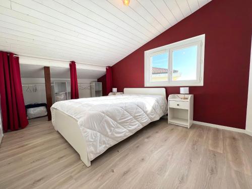 une chambre avec un lit blanc et un mur rouge dans l'établissement Ô COURANT - T3 terrasse vue océan, à Mimizan