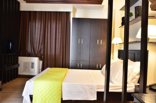 a bedroom with a bed with a yellow blanket on it at Oriental Zen Suites in Manila