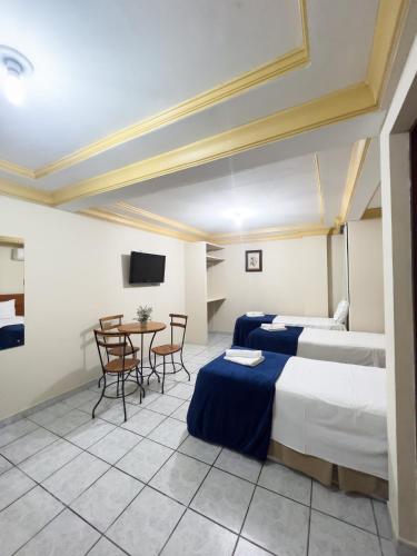 a hotel room with two beds and a table at Central Hotel in Campina Grande