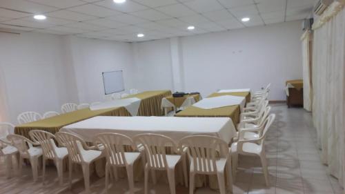 uma sala com mesas e cadeiras brancas e um ecrã em Hotel Tame Real em Tame