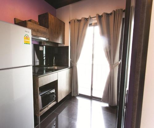 een kleine keuken met een koelkast en een raam bij Varrzon Residence Srinakarin 56 in Bangna