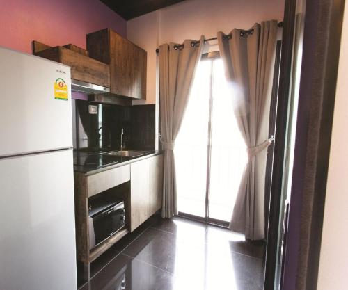a small kitchen with a refrigerator and a window at Varrzon Residence Srinakarin 56 in Bangna