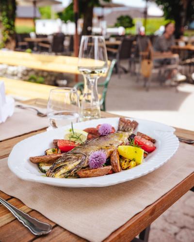 a plate of fish and vegetables on a table with wine glasses at Hotel Kaiserhof in Anif