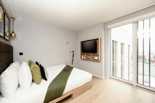 a bedroom with a bed with a tv on the wall at Wilde Aparthotels Manchester City Centre in Manchester