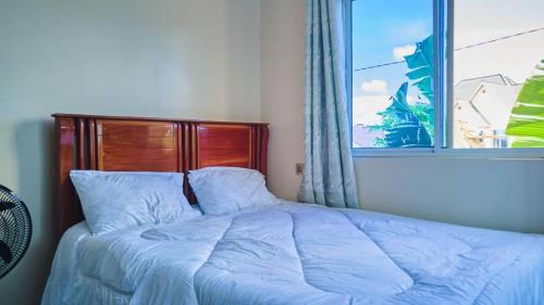 Bett in einem Schlafzimmer mit Fenster in der Unterkunft SULTANA APPARTMENTS in Mwanza