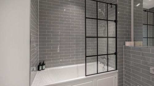 a shower with a white tub in a bathroom at Priority Suite - Modern 2 Bedroom Apartment in Birmingham City Centre - Perfect for Family, Business and Leisure Stays by Estate Experts in Birmingham