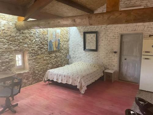 une chambre avec un lit dans un mur de pierre dans l'établissement Loft atypique, à Saint-Montan