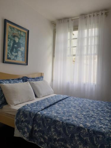 a bedroom with a bed with a blue blanket and a window at Casa Feliz in Campo Alegre