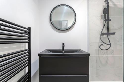 La salle de bains est pourvue d'un lavabo noir et d'un miroir. dans l'établissement Saint-Just, à Lyon