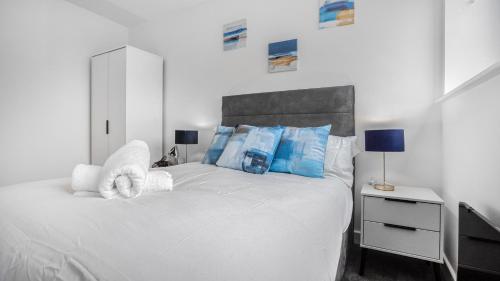 een slaapkamer met een wit bed met blauwe kussens bij Priority Suite - Modern 2 Bedroom Apartment in Birmingham City Centre - Perfect for Family, Business and Leisure Stays by Estate Experts in Birmingham