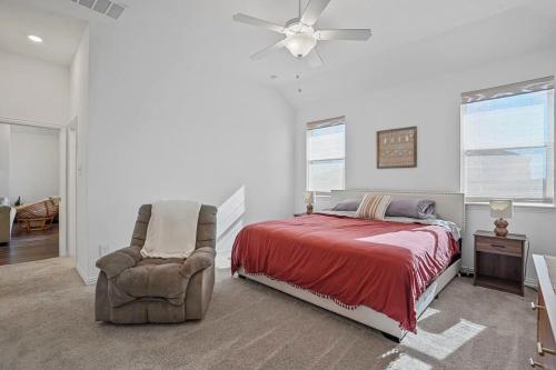 a bedroom with a bed and a chair and a ceiling fan at Sleeps 12~Private Yard~Dog Friendly~Charcoal Grill in Haslet
