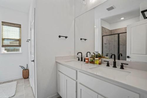 a white bathroom with a sink and a mirror at Sleeps 12~Private Yard~Dog Friendly~Charcoal Grill in Haslet