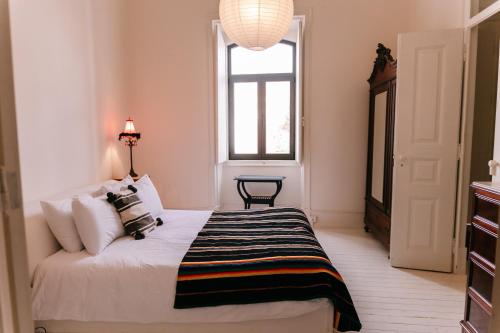 ein Schlafzimmer mit einem Bett mit einer schwarzen und weißen Decke in der Unterkunft Casa Melchior in Portimão