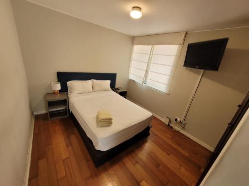 a small bedroom with a bed and a television at Espacio Luxury Apartments- Edificio Alcanfores in Lima