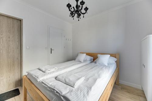 a bedroom with a large bed with white sheets and a chandelier at Grobla Centrum 1 by Grand Apartments in Gdańsk