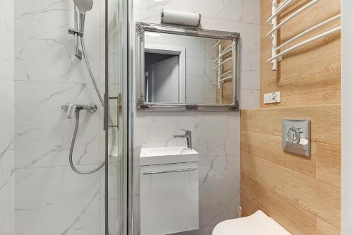 a bathroom with a shower and a sink and a mirror at Grobla Centrum 1 by Grand Apartments in Gdańsk