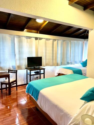 a bedroom with two beds and a desk with a television at Hotel Concorde in Punta del Este