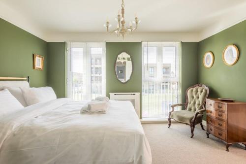 a bedroom with green walls and a bed and a chair at Stunning 3 Bedroom Home with Terrace & Parking in Trumpington