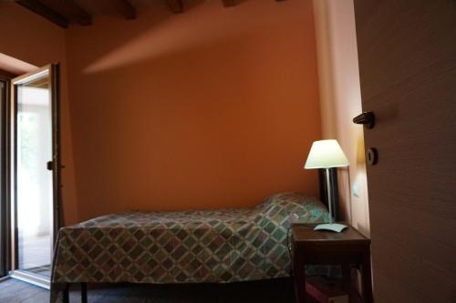 a bedroom with a bed and a lamp next to a door at Le Gatte in SantʼUrbano