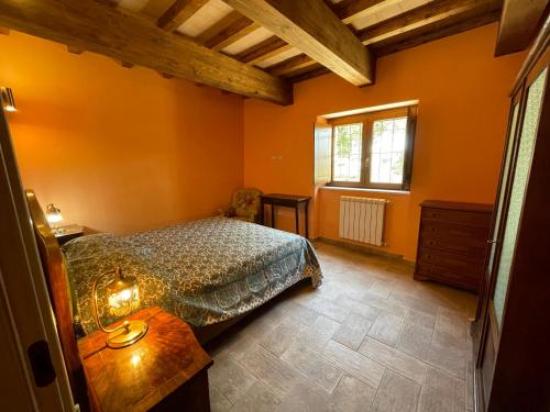 a bedroom with orange walls and a bed and a table at Le Gatte in SantʼUrbano