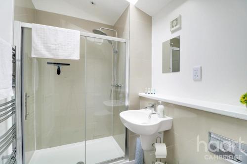 a white bathroom with a shower and a sink at Lovely 1 Bedroom Flat with Free Off Road Parking in Chesterton