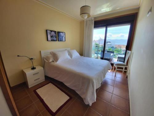 - une chambre avec un lit blanc et un balcon dans l'établissement Apartment with direct access to the beach(WIFI), à Sanxenxo