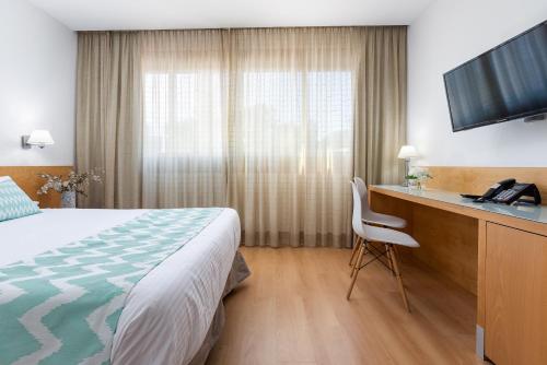 a hotel room with a bed and a desk with a television at Daniya Alicante in Alicante