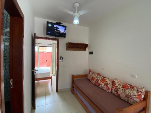 a living room with a couch and a tv on the wall at Residencial Porto di Lázaro in Ubatuba